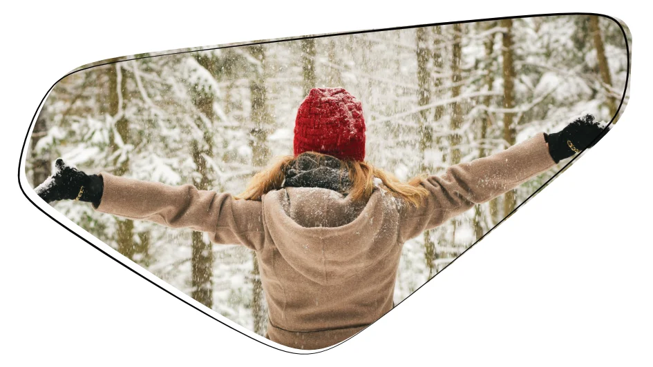 Frau im verschneiten Wald mit roter Mütze